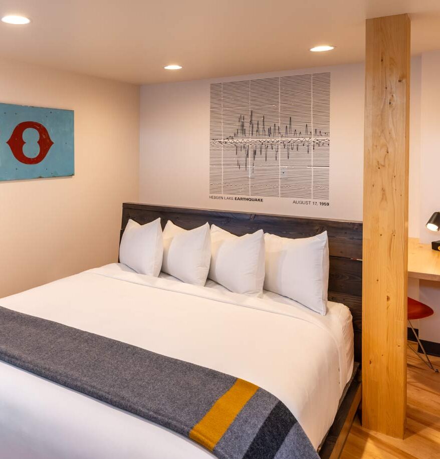 Interior view of our downtown Bozeman hotel suite. Wooden flooring & accents, king sized bed, wall art, and wooden desk