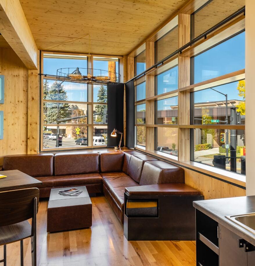 Inside a suite lounge at our downtown Bozeman hotel. Leather seating under large windows overlooking main street, and small table in front