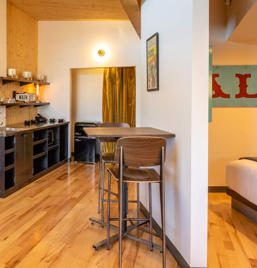 Inside the suite lounge at our downtown Bozeman hotel. Wooden accents, countertop & sink, small wooden desk, with large windows overlooking Main Street.